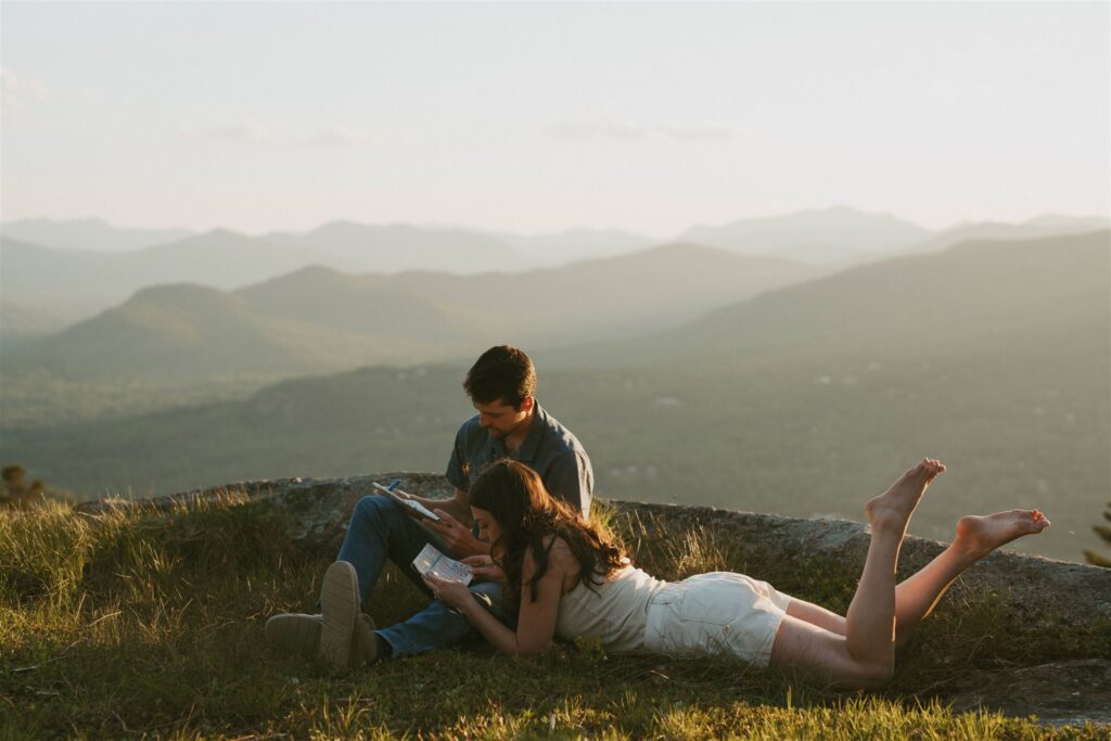 Couple having a slow moment doing crossword puzzles on a mountain top during their engagement session. 