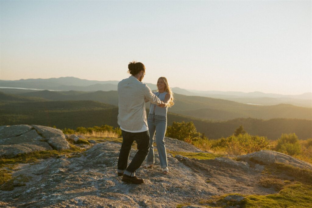 Couple swinging around during their mountain top engagement session in the White Mountains. 
