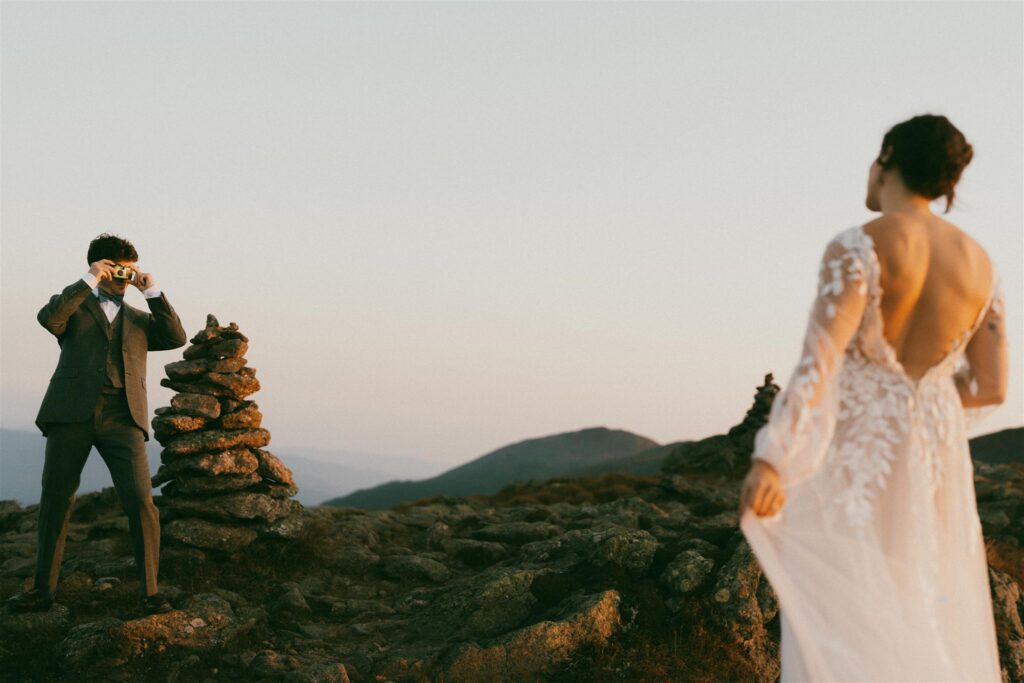 Groom taking a photo of his partner during a White Mountains elopement in New Hampshire