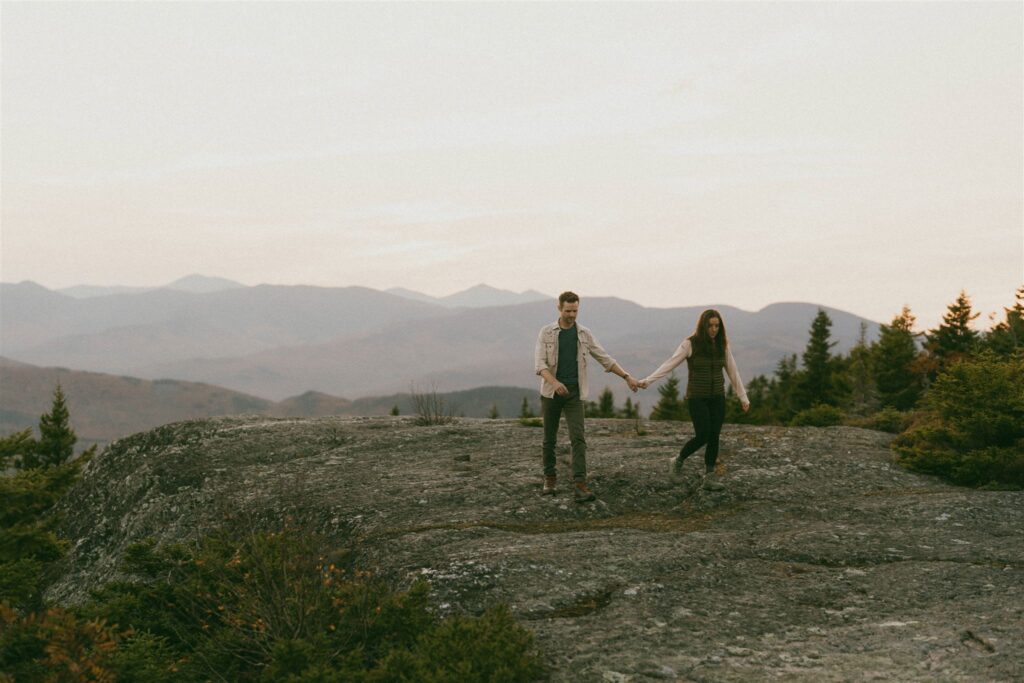 Couple walking hand in hand on top of a mountain during their adventure session in the White Mountains. 