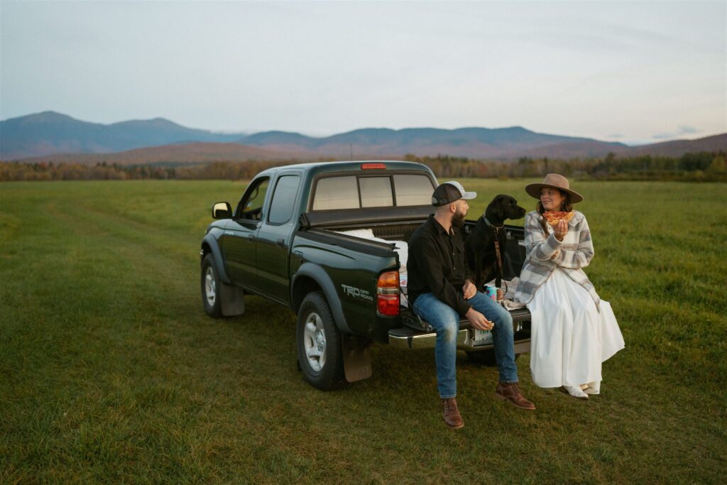 Couple enjoying pizza on the back of their truck during their engagement session in the White Mountains. 