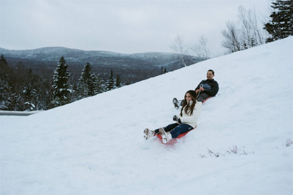 Couple sledding during their winter White mountain engagement. 