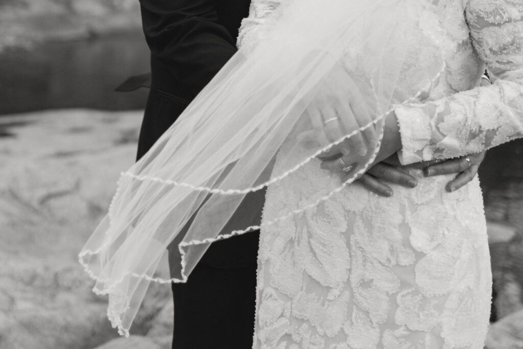 Close-up of a couple holding each other, with a veil moving in the wind