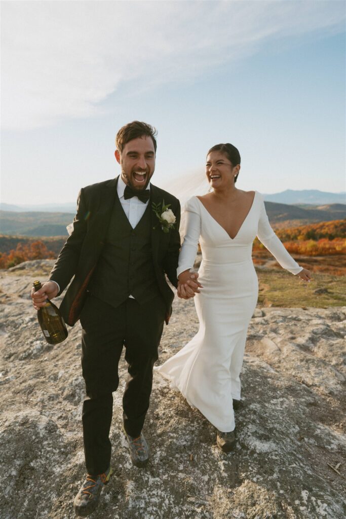 Couple walking across a rocky mountain summit during a fall elopement in the White Mountains of New Hampshire