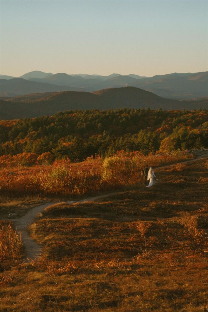 Couple walking along a trail with mountain views during an autumn elopement in the White Mountains