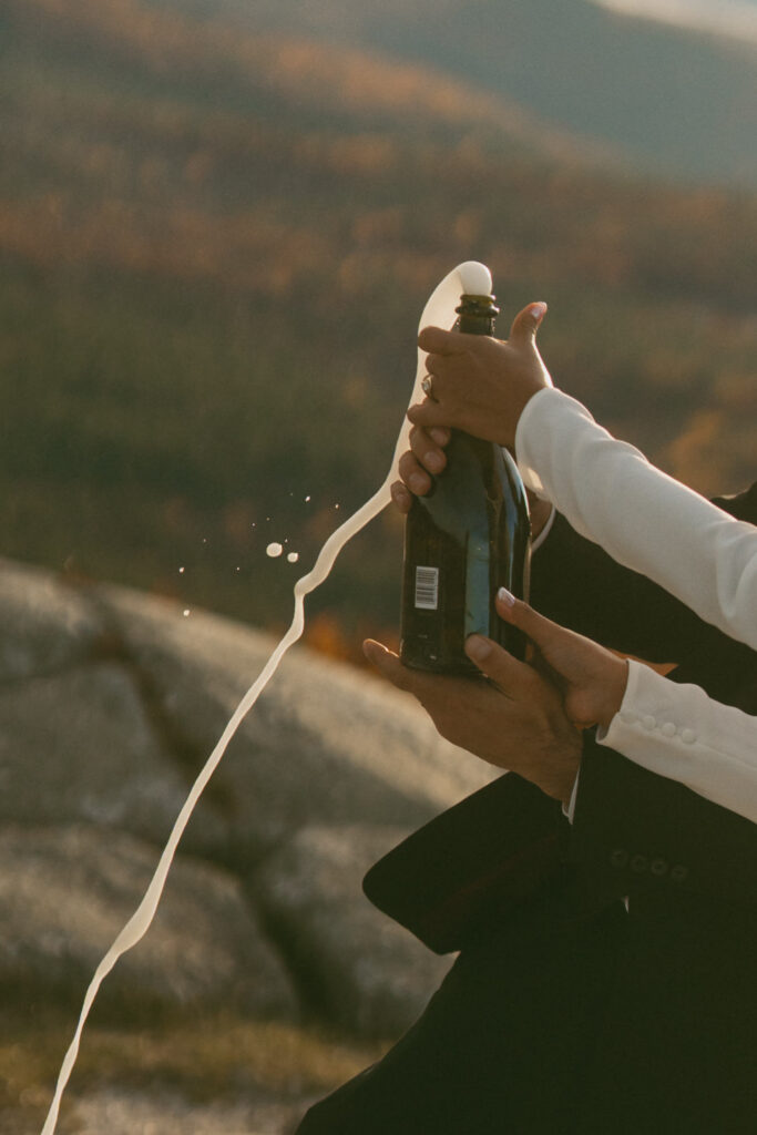 Close up of champagne popping during sunset elopement in New Hampshire