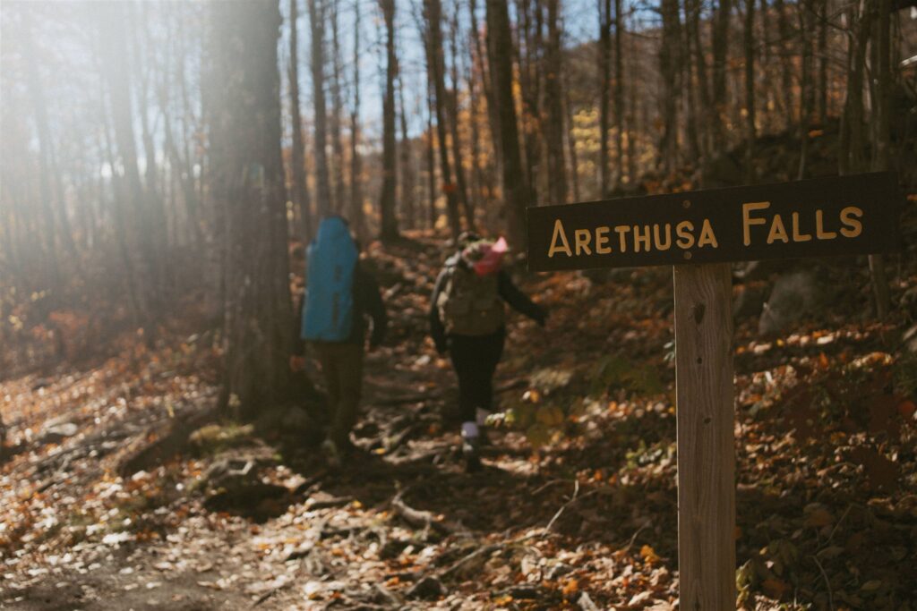 Couple hiking to Arethusa Falls for a New Hampshire elopement in fall