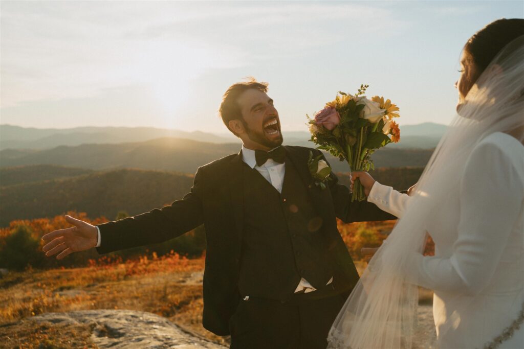 Couple celebrating on a mountain overlook during their fall elopement in the New Hampshire White Mountains