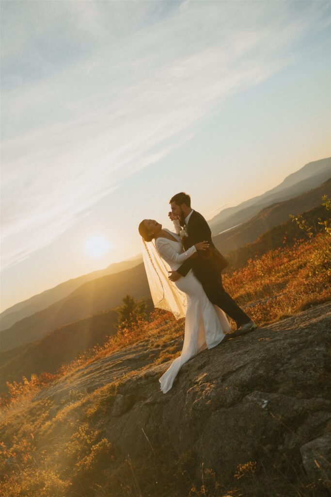 Couple celebrating together on a mountain overlook during a fall elopement in New Hampshire