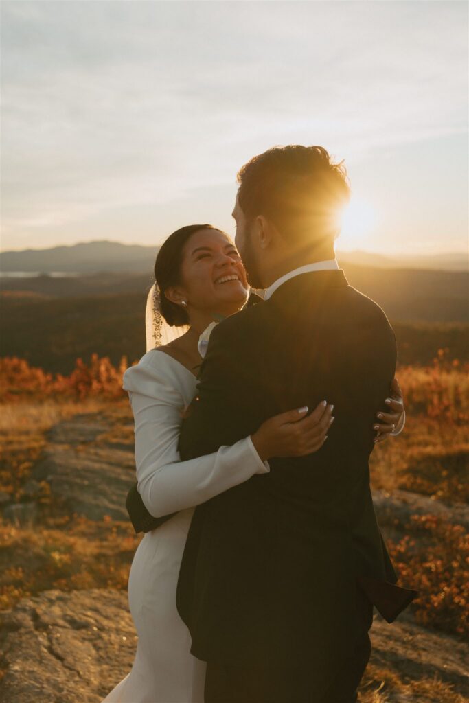 Couple embracing at sunset on a mountain summit during their New Hampshire elopement
