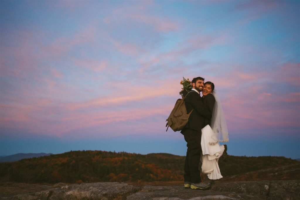 Couple hugging on mountain summit at sunset during New Hampshire fall elopement in the White Mountains