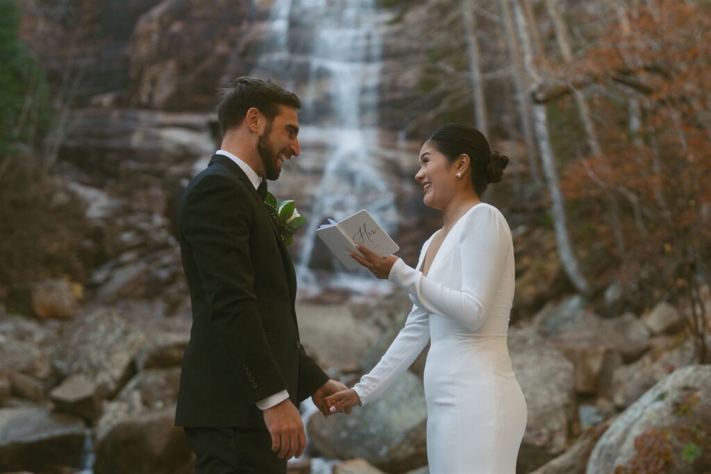 Couple reading vows during a fall elopement at Arethusa Falls in the White Mountains of New Hampshire