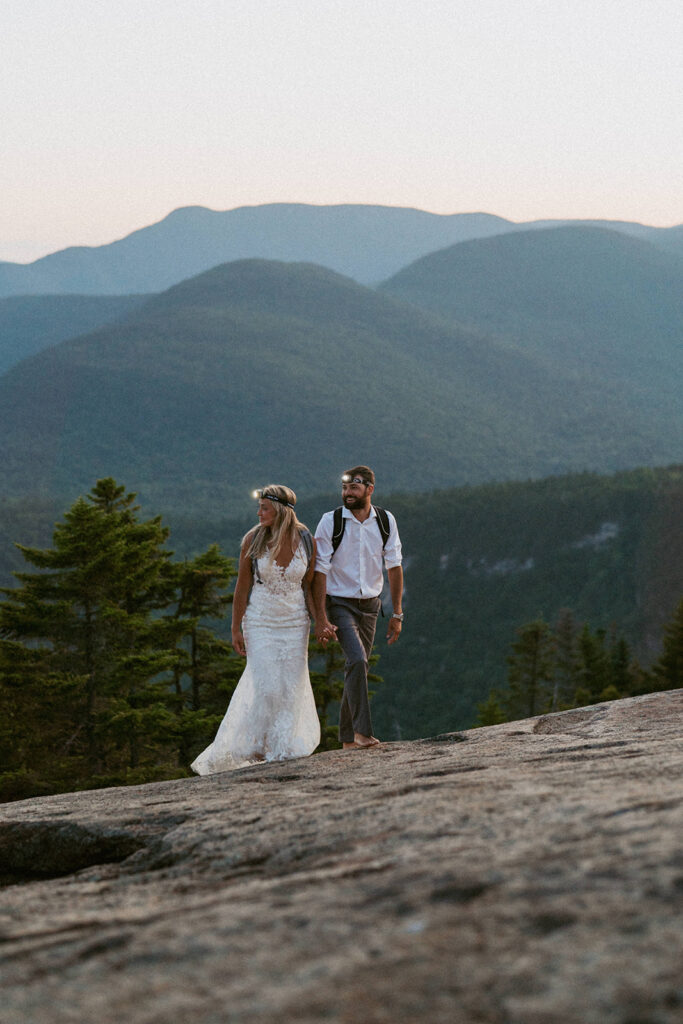 Couple hiking with headlamps at sunrise during their White Mountains elopement.