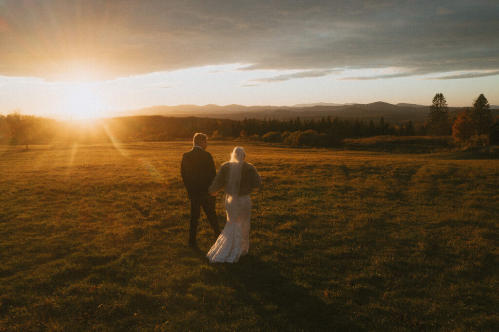 Couple walking through a field at sunset during a fall White Mountains elopement