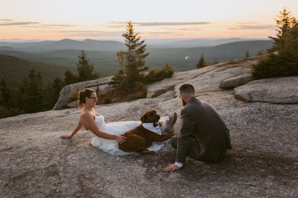 Couple relaxing on a granite overlook with their dog during their elopement day